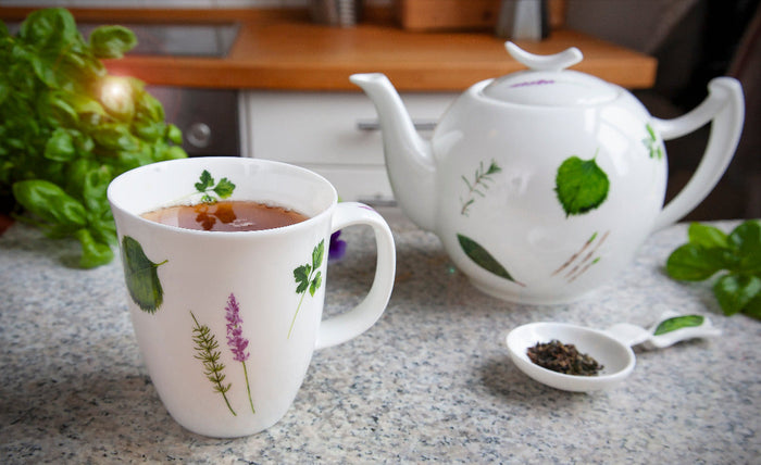 Hochwertige Wohnaccessoires Prima Vera: Tasse und Teekanne mit botanischem Design auf Steinarbeitsplatte.