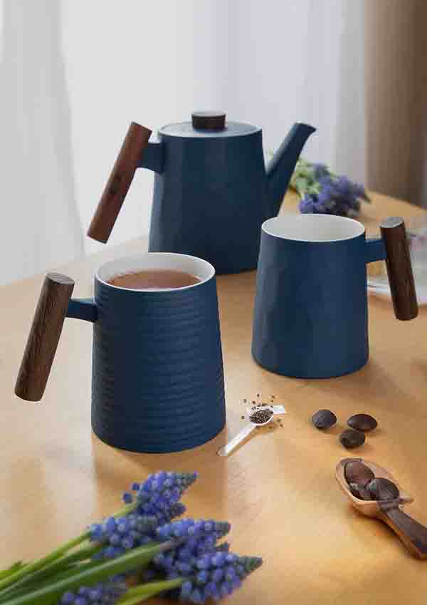 Blu Teekanne und Becher Holzgriff auf einem Holztisch mit Lavendel und Kaffeebohnen.